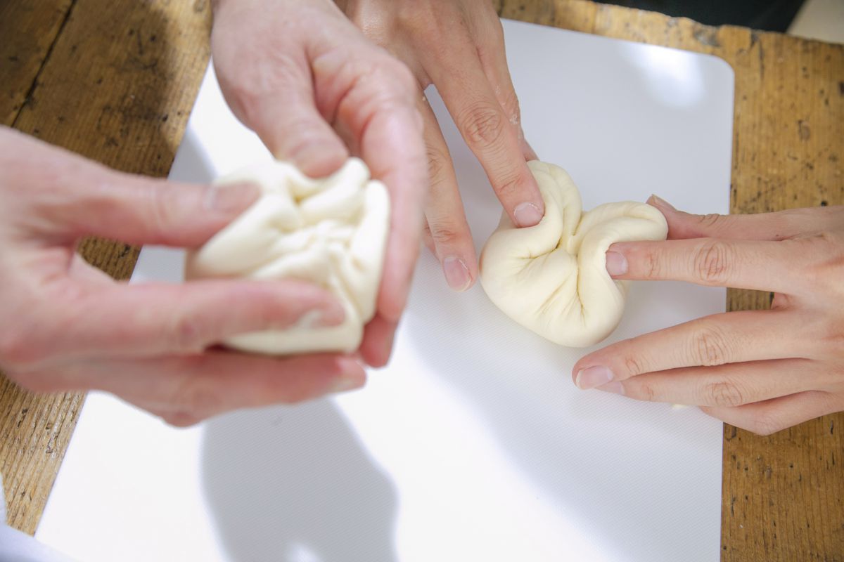 平らにした生地の端を、左右、上下とつまんで中央に寄せながら丸めていくのがポイント