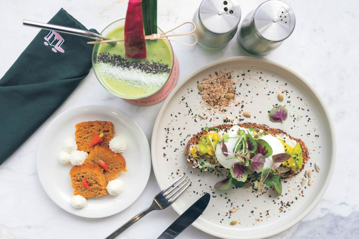 華やかな盛りつけは写真映え必至♪アボカドとドラゴンフルーツの緑と赤のコントラスト、プレートに咲くエディブルフラワーの組合せがおすすめです。グリーンスムージー12万VND、穀物パンを使ったスマッシュド・アボカド16万VND、キャロットケーキ10万VND