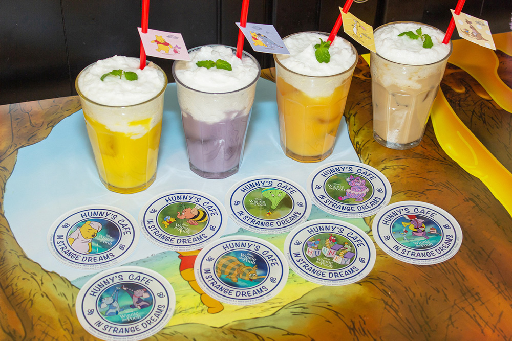 左から、「プーさん」はちみつヨーグルトドリンク　890円／コースター付き：1490円、「イーヨー」ぶどうヨーグルトドリンク　890円／コースター付き：1490円、「ラビット」キャロットドリンク　890円／コースター付き：1490円、「カンガ」と「ルー」カフェラテ　890円／コースター付き：1490円（すべて税抜）