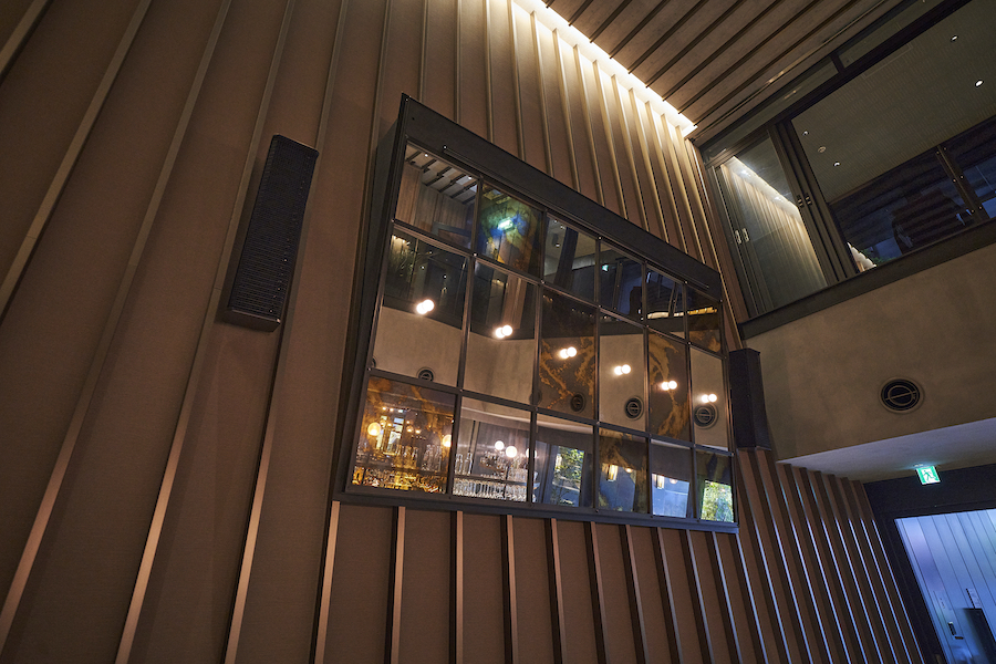 レセプションに繋がる吹き抜け部分には、スクリーンとスピーカーが備わる