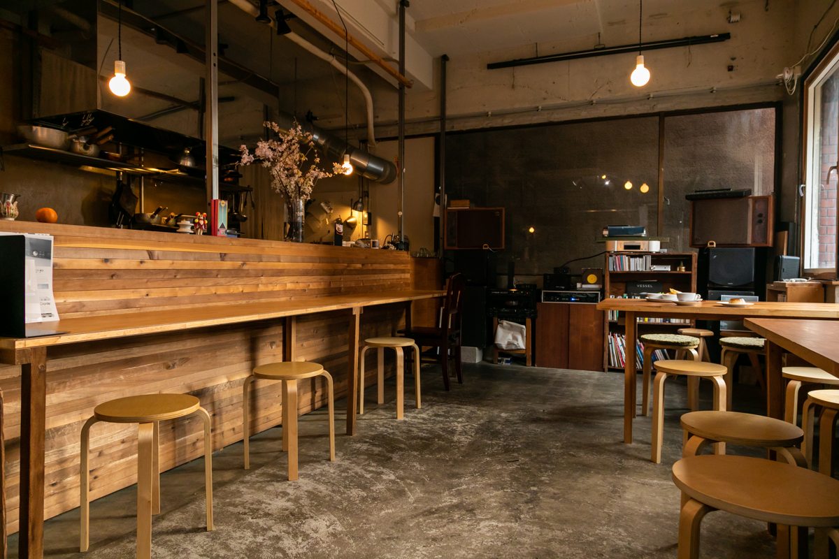 コンクリート打ち放しに木製のカウンターとテーブル席のおしゃれな店内