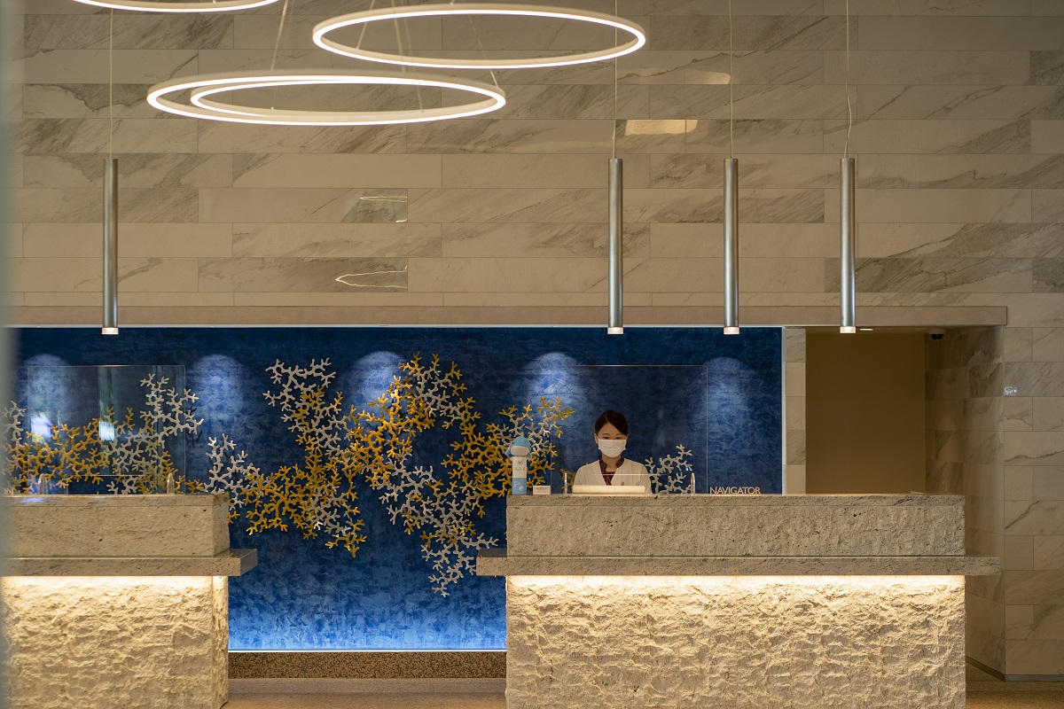 フロントの壁面にあしらわれたサンゴのアート、バブルリングを思わせる照明にも注目