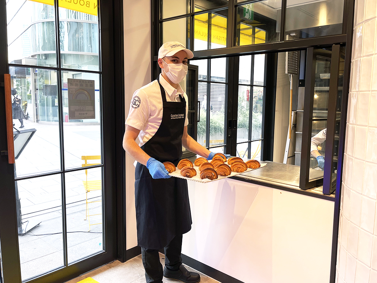 焼きたてのパンを運ぶ、店長のダミエンさん