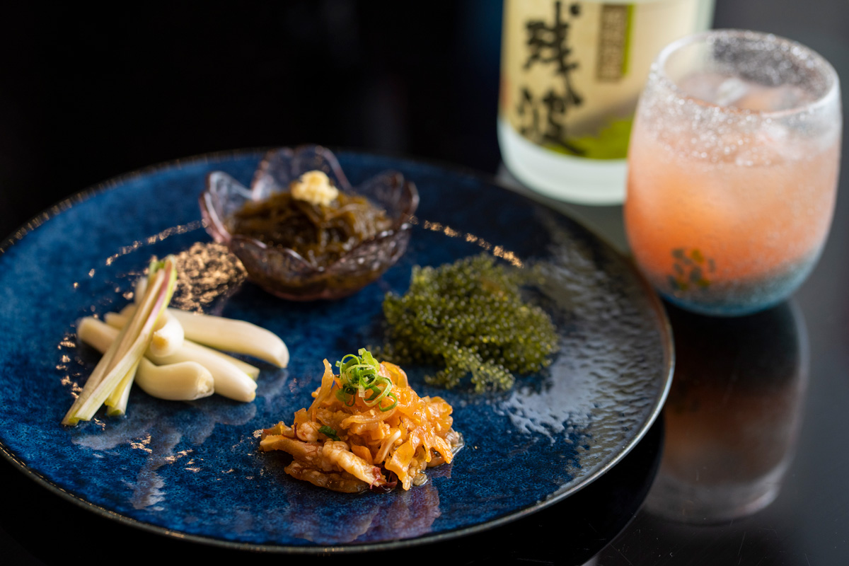 県産珍味プレート（ピリ辛ミミガー、島らっきょう浅漬け、もずく酢、海ぶどう）　1200円、娘ジントーヨー（泡盛×グァバジュース）　700円