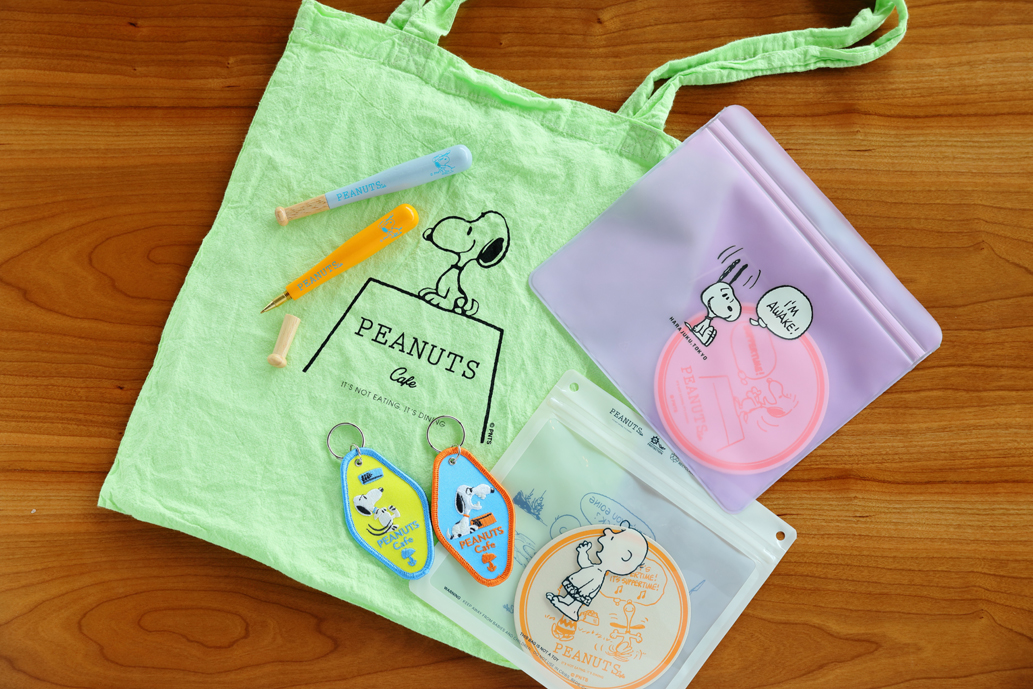 左からPEANUTS Cafe OSAKA エコトート グリーン1760円（大阪限定）、PEANUTS Cafe×penco バットペン1本1320円、PEANUTS Cafe ワッペンキーホルダー1個1100円、Pokeジッパーバッグ1210円、PEANUTS Cafe SSK TPU デイリーポーチ1650円
