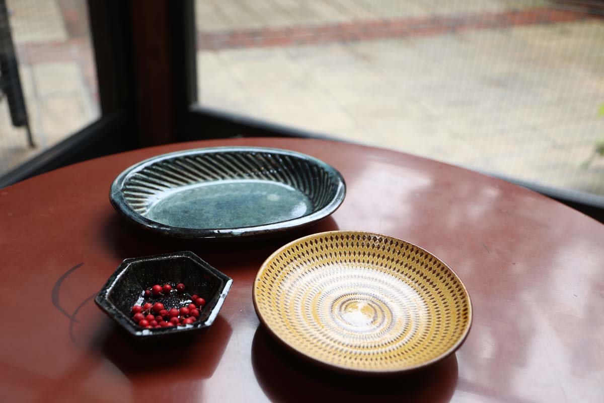 奥から時計まわりに：湯町窯 楕円皿5280円、小石窯 丸皿1870円、白田窯 六角皿2860円