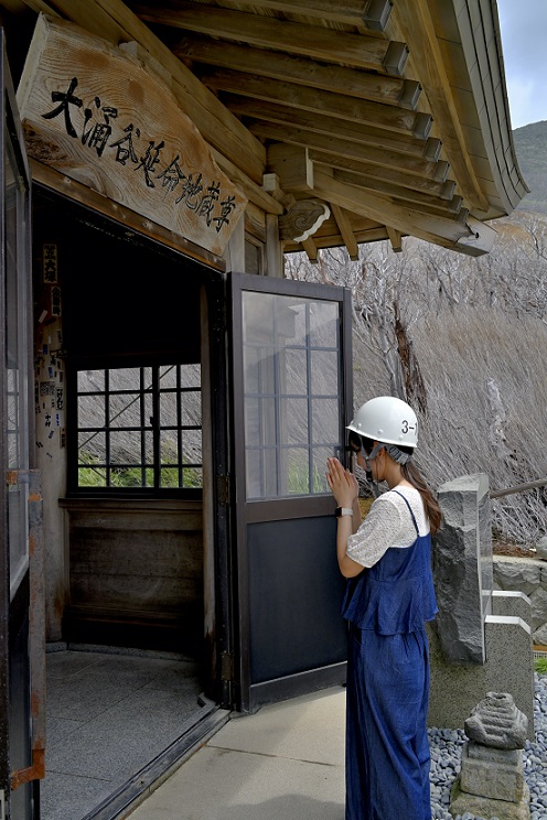 ヘルメットを被って地蔵に祈る様子