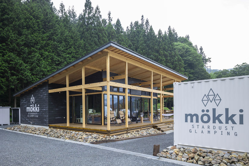 駐車場に隣接する管理棟。ヒノキ材の木の質感が背景のグリーンに馴染みます