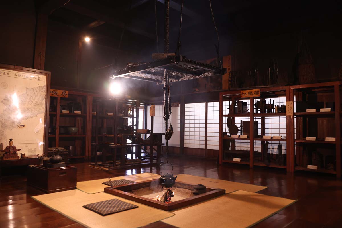 囲炉裏のまわりに生活用具が展示されている