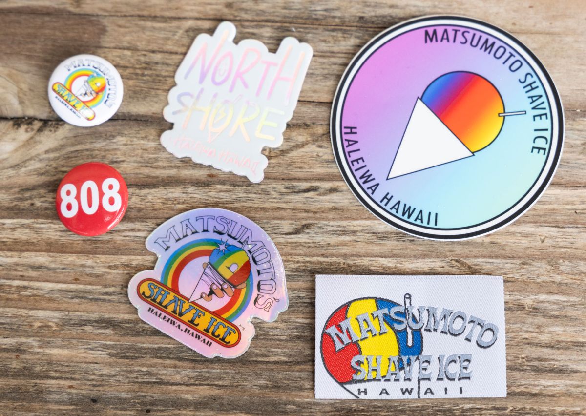 「オリジナルステッカー」各$1、「オリジナル缶バッジ」各$1