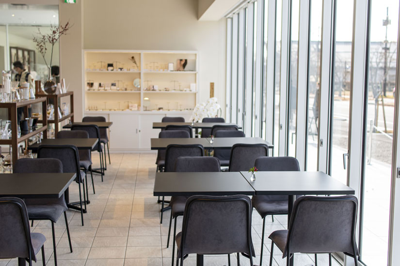 ガラス張りが開放的なカフェ。モノトーンの家具をゆったりレイアウト