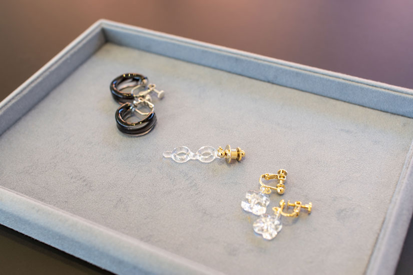 軽井沢安東美術館限定アクセサリーも。左から、フジタのフープピアス乳白色ブラック10,780円、フジタのメガネ4,950円、平和の聖母礼拝堂フラワー8,360円