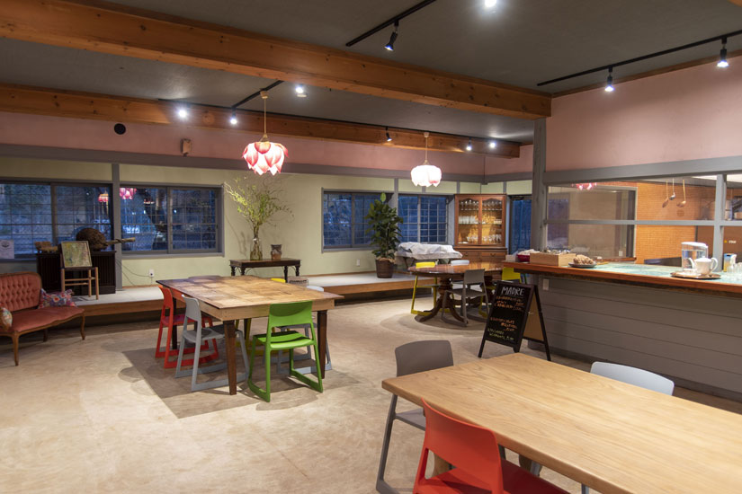 大テーブルを3卓レイアウト。シンプルなテーブルにカラフルな椅子が並びます