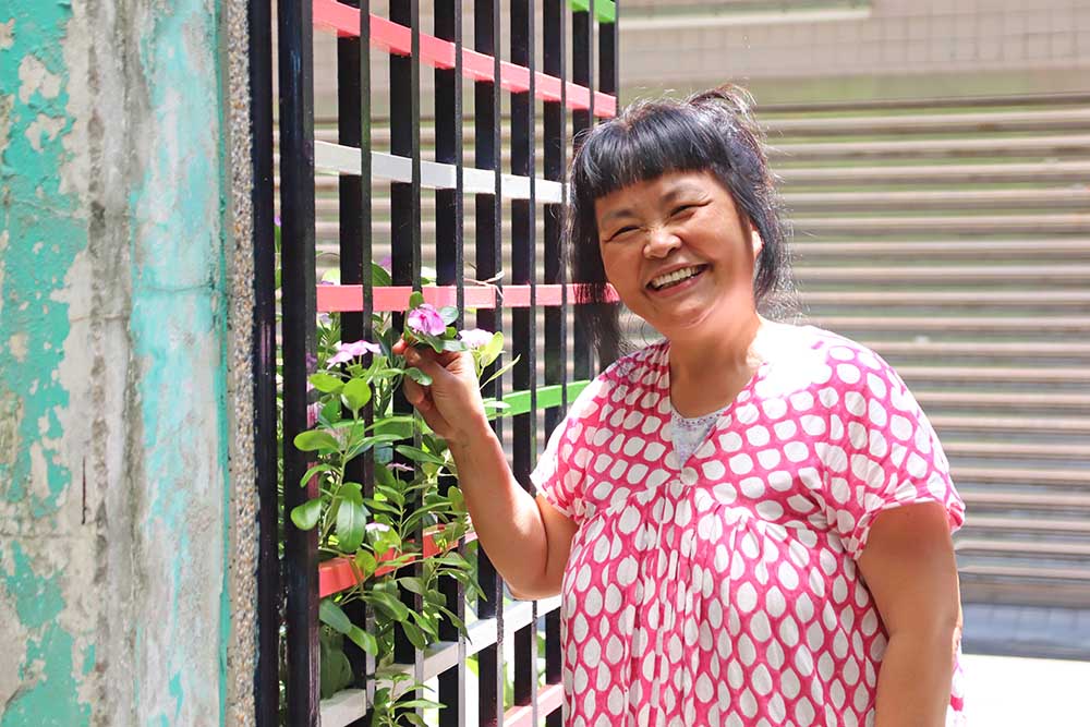 「布調」オーナーの陳さん。お店のロゴになっているお花を紹介してくれました
