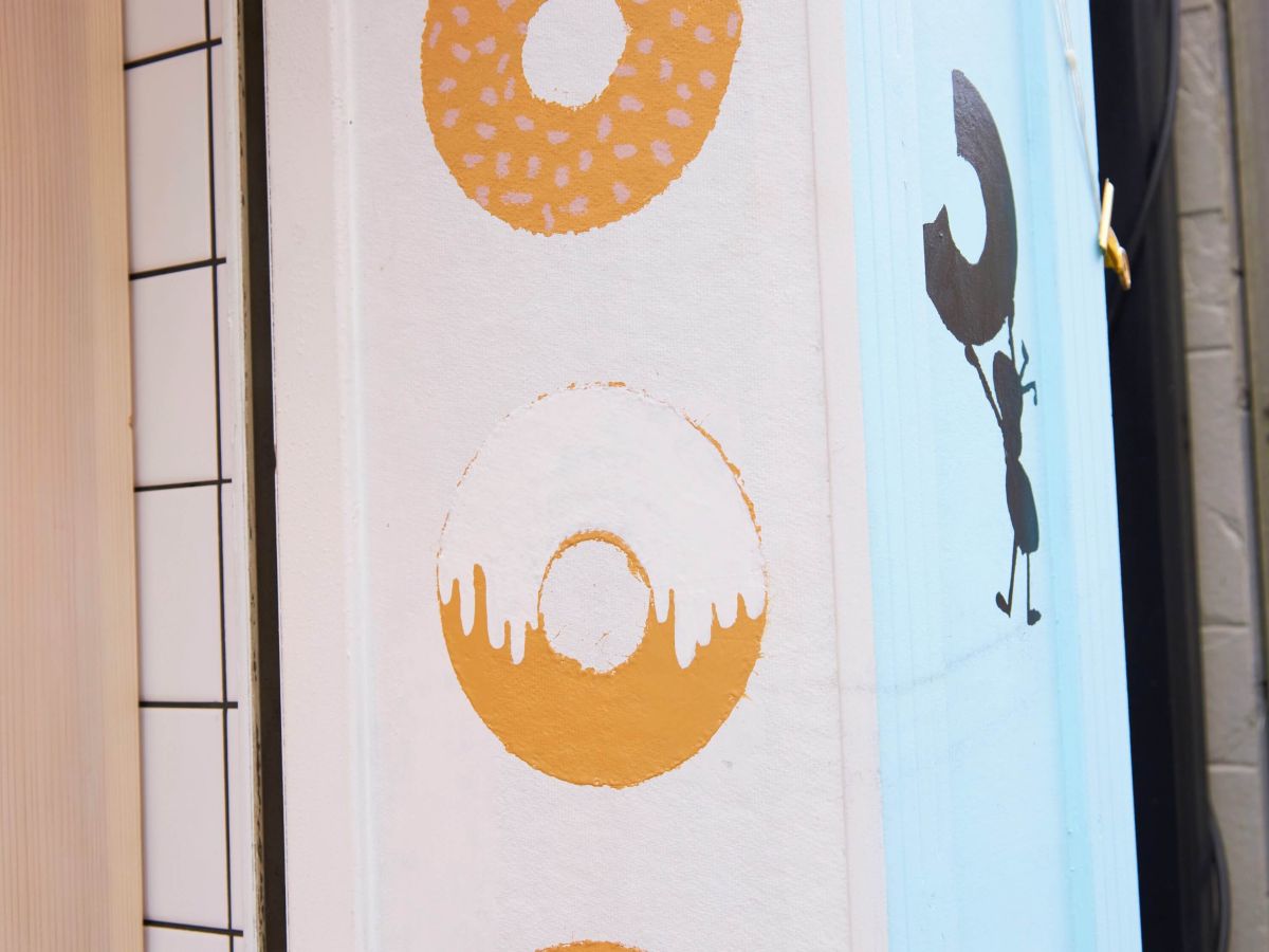 水色の外壁に描かれたドーナツとアリのイラストが目印