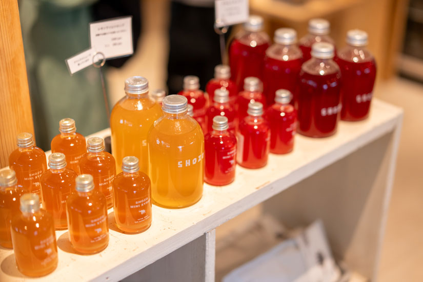 レモンライムやプラムのシロップ(ミニ450円〜)、オリジナルの雑貨はおみやげにぜひ