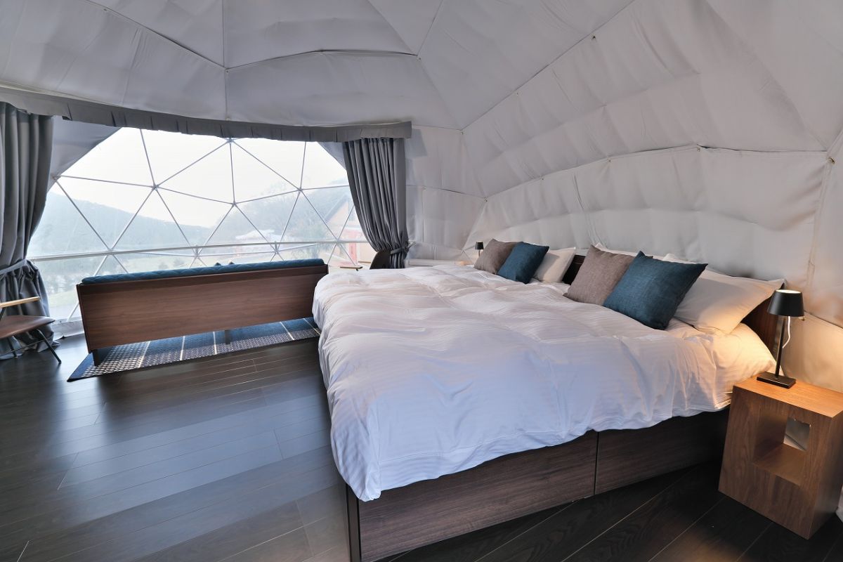 グランBASEのドームテント内。ゆったりした広さで大きなベッドとソファ付き。1棟基本料金（2名）51,000円～　定員：5名