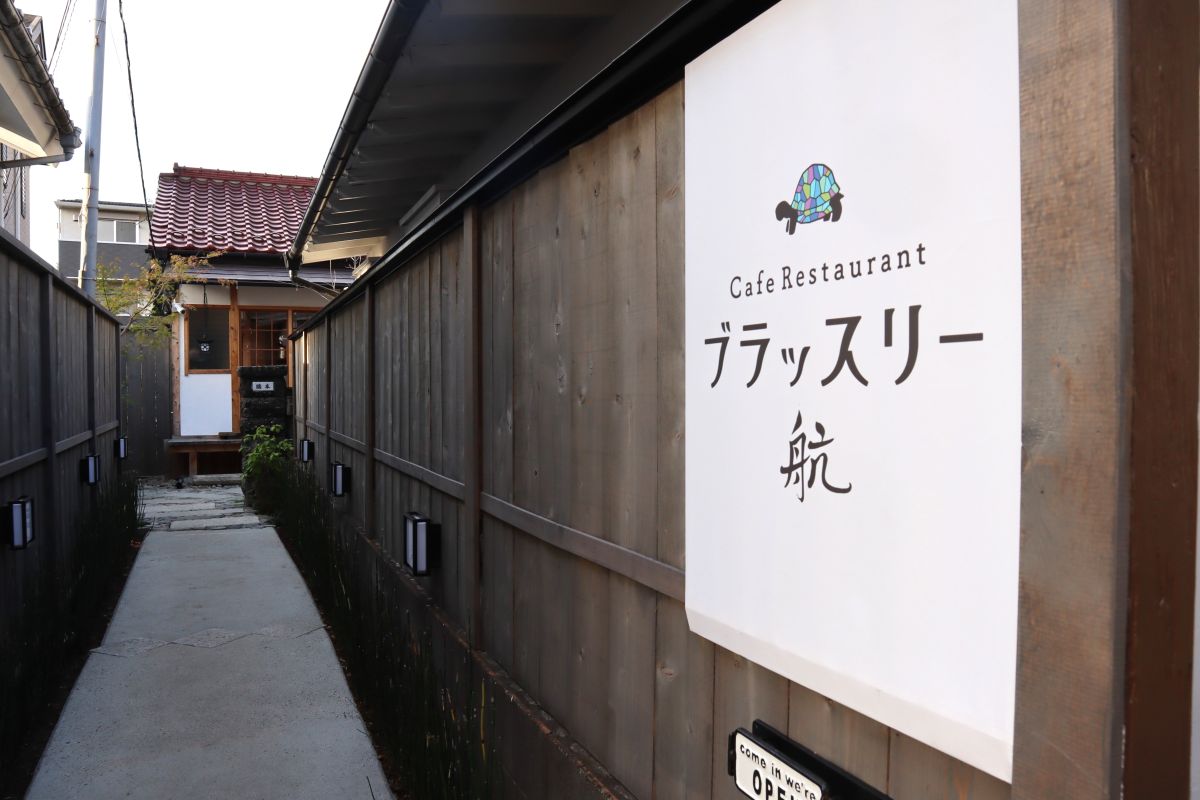 塀に囲まれた細い道の先にある