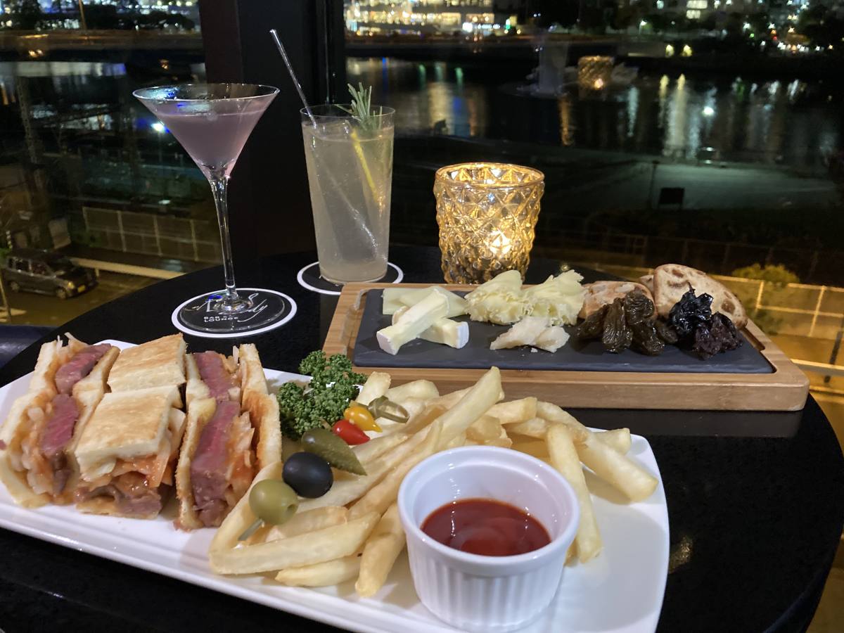 （ドリンク左）「ブルー・ムーン」1500円、（ドリンク右）「メロディー・レモンサワー」1500円、（手前）「厚切りローストビーフサンド」2900円、（奥）「チーズプレート」2100円