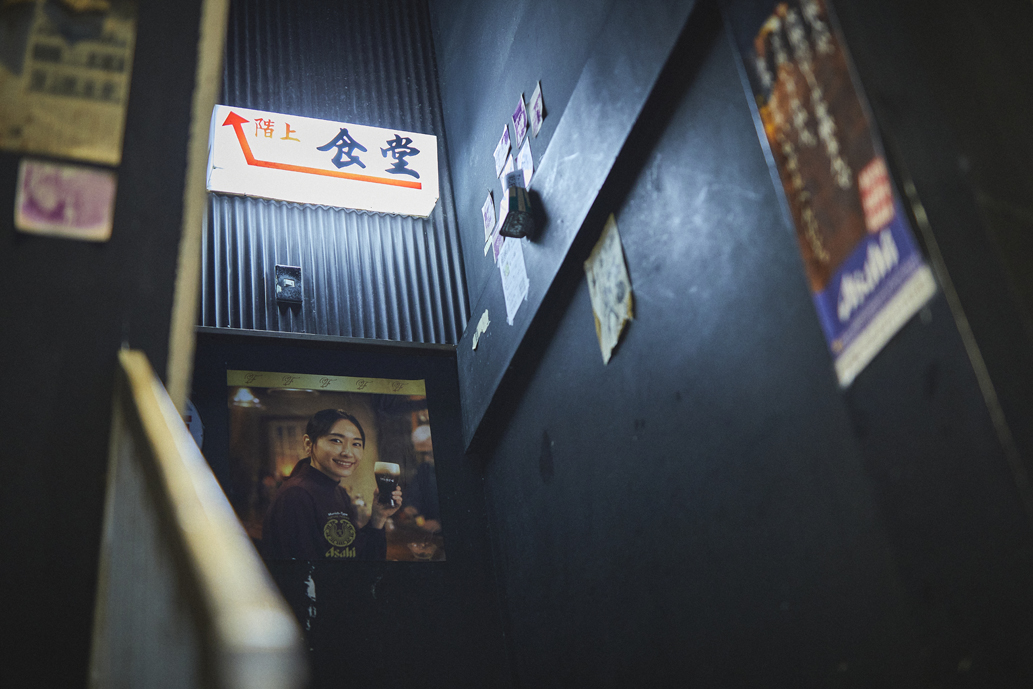 昔の写真や看板などが飾られた雰囲気のある階段を上る