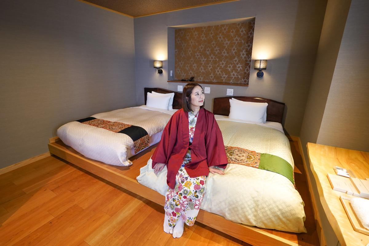 離れ「花」TypeBの温泉露天風呂付き和洋室。離れベッドルームには、古帯をリメイクしたベッドスローがアクセントに