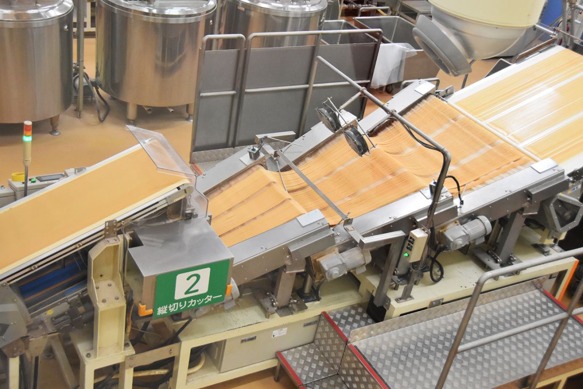 縦に長いプリッツが流れていく【2】縦切りカッター。ココで小さな切り込みを入れていきます