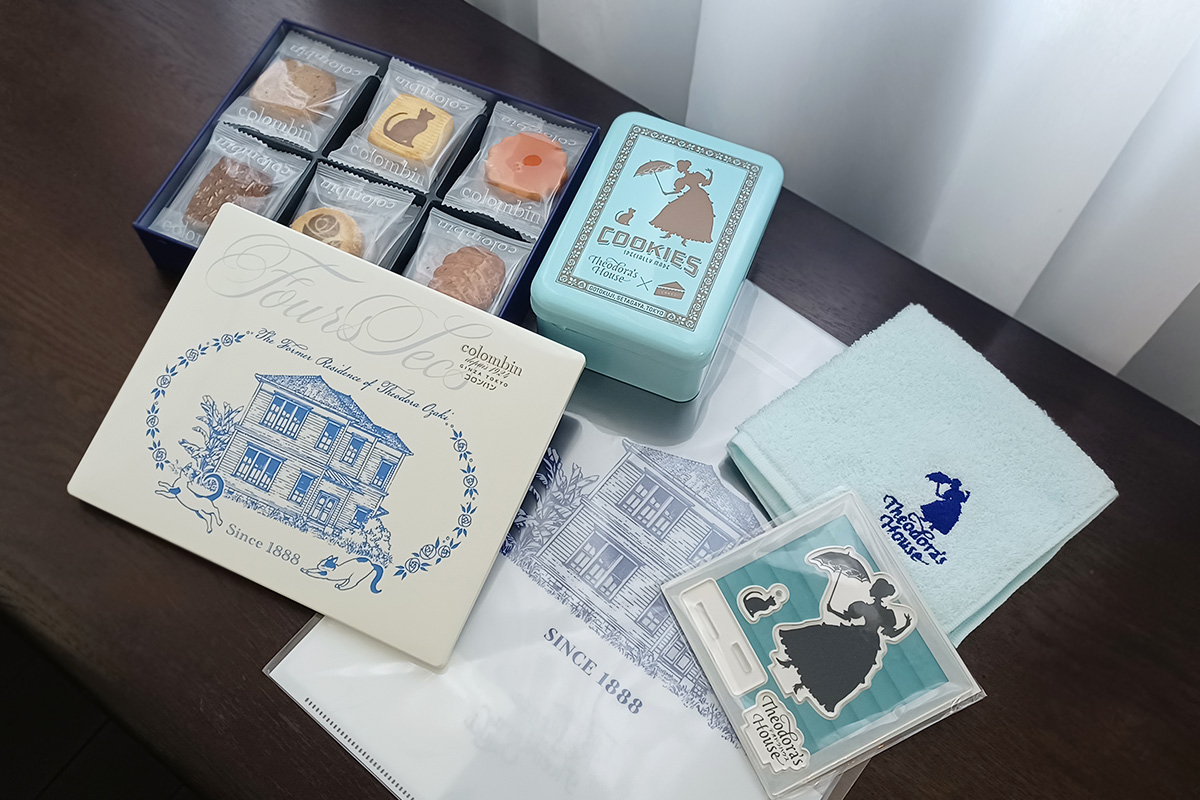 (写真左から)「旧尾崎テオドラ邸オリジナルクッキー缶」2200円、「コラボクッキー缶」3500円、「旧尾崎テオドラ邸オリジナルクリアファイル」550円、「旧尾崎テオドラ邸オリジナル刺繍ハンカチ(ブルー)」1320円、「旧尾崎テオドラ邸オリジナルアクスタ&アクキーセット」1540円