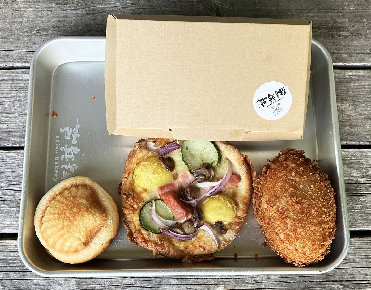 下左から、貝がらのクリームパン180円、Pizzaマミレーナ310円、特製カレーパン270円。上の箱には青森りんごのアップルパイ790円