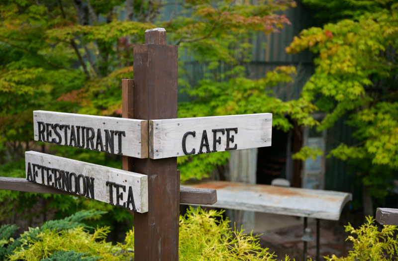 カフェへはサインを目印に。アプローチのモミジは夏でもほんのり色づいてきれい
