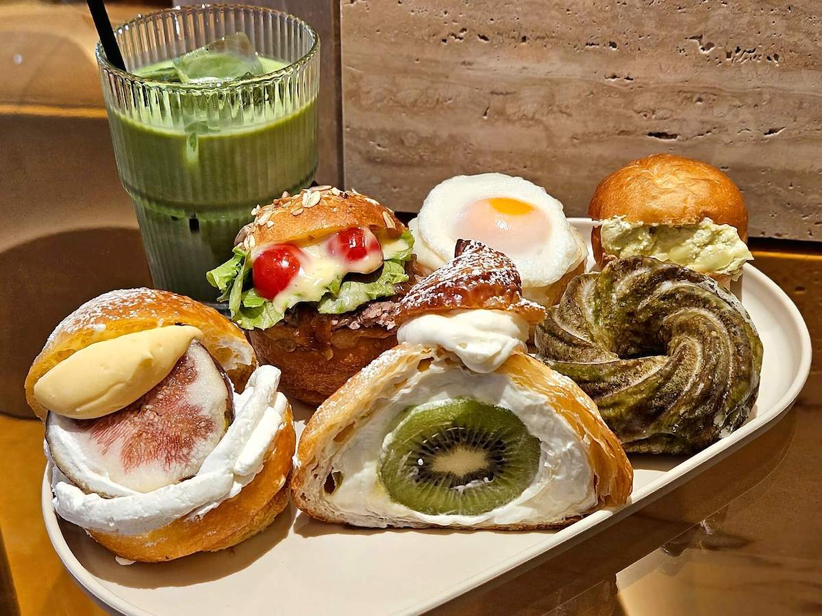 （左手前から反時計回りに）「季節のフルーツサンド（いちじく）」429円、「フルーツクロワッサン」496円、「焼きフレンチクルーラー抹茶」270円、「ピスタチオ練乳」302円、「クロックマダム」356円、「照り焼きバーガー」410円