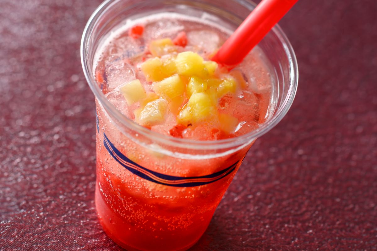 プラザパビリオン・レストラン「スパークリングカクテル（ラズベリーリキュール＆パイナップル）」単品830円 ラズベリーリキュールの赤と、パイナップルの黄色が色鮮やかなカクテル。食事ともバランスのとれる甘酸っぱさで、ゴロゴロとした果肉の食感も楽しめます