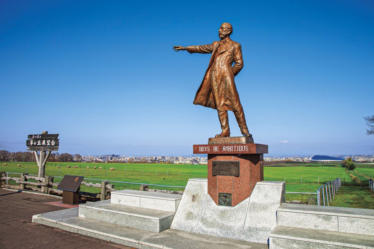 クラーク博士像の背後に、石狩平野を見渡す雄大な景色が広がる