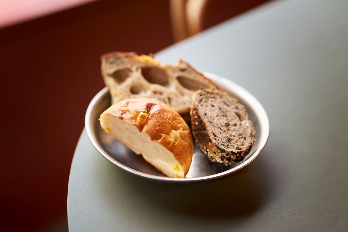 おかわり自由の「パン盛り合わせ」330円。（写真左手前から時計回りに）「北海道美瑛産とうもろこしのコーンパン」（手前左）、「オレンジ・カルダモンとマルコナアーモンド」（奥）、「有機胡麻のパン」（手前右）