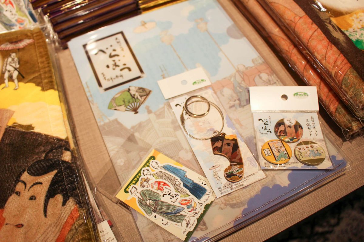 （写真下左から）「ステッカー4枚セット衣装画」、「べらぼう 木札ワイヤーキーホルダー」、「べらぼう 缶マグネット3個セット」