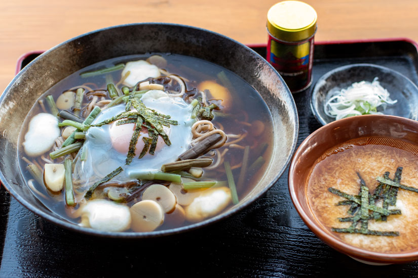 温かいそばの「しげのや」1490円。山菜、卵、力餅が乗って、とろろ小鉢も付く