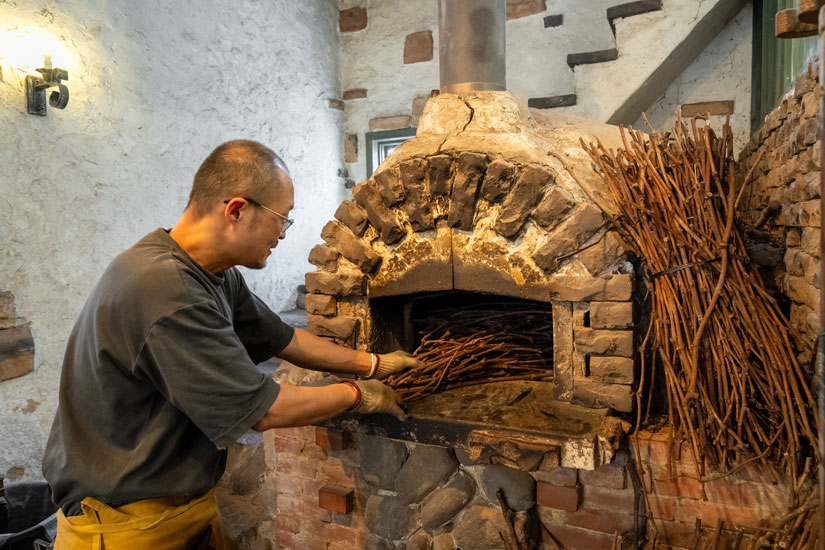 余熱の温度を調整する際に使うのは、山梨のブドウの木の枝。季節や天気によっても熱の上がり方は異なるため、窯の温度調節は職人技