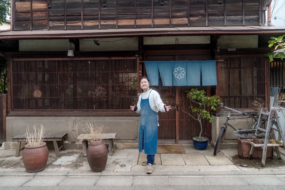 オーナーの輪島さんとお店の前で1枚パチリ。青いのれんとデニムエプロンがシンクロしていい感じ