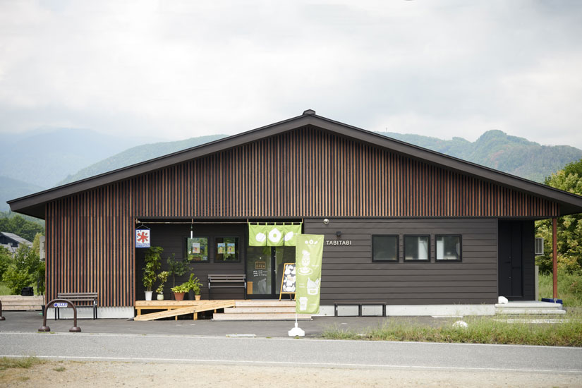 山を背に立つ和モダンな建物。グリーンの暖簾が目印