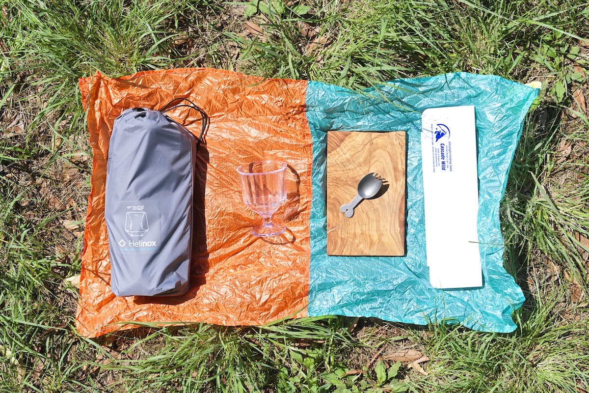 左から、折りたたみ式アウトドアチェア、割れないコップ、カッティングボードとカトラリー、折りたたみ式ミニテーブル。下に敷いてあるのはポケッタブルなレジャーシート