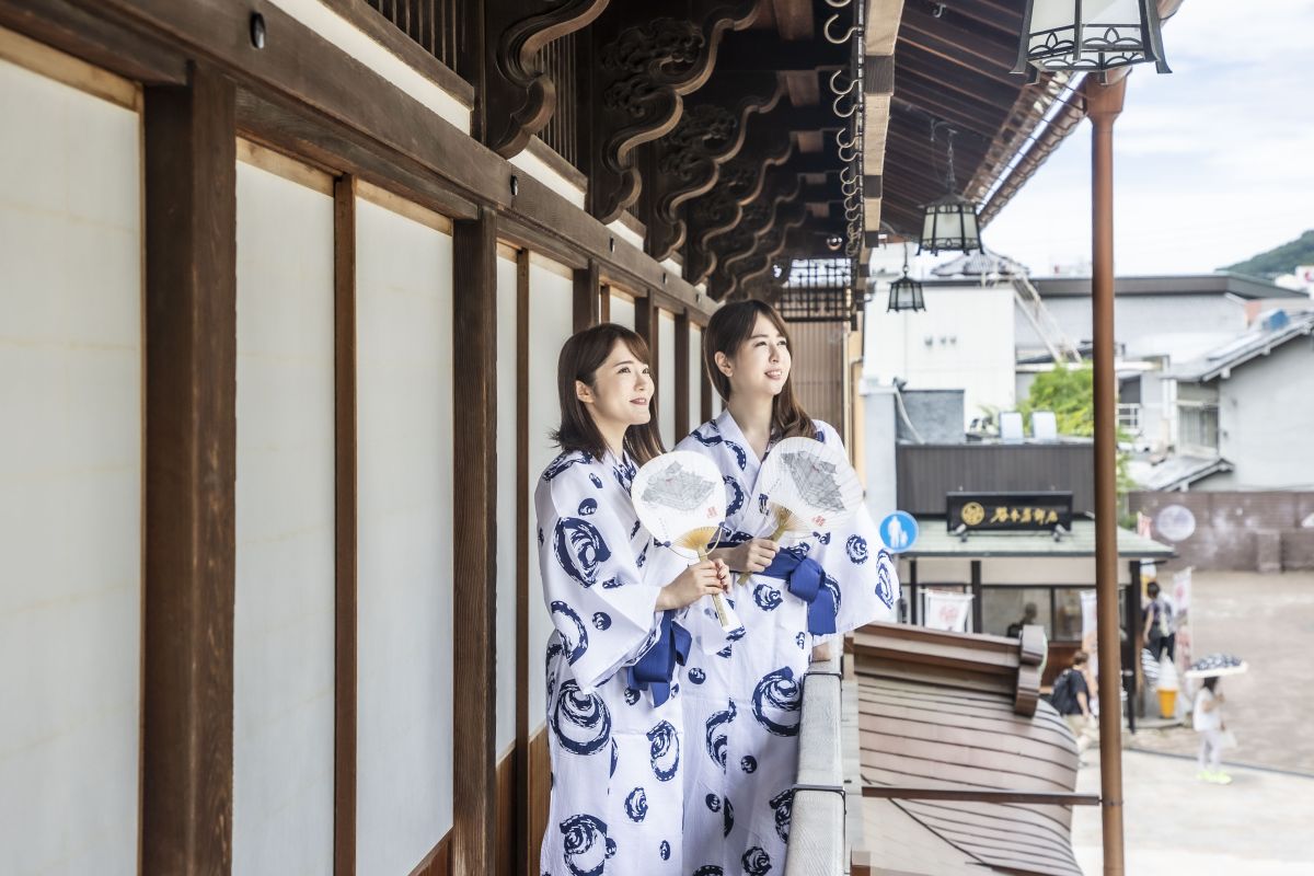 休憩室の濡れ縁から温泉街を眺める女性