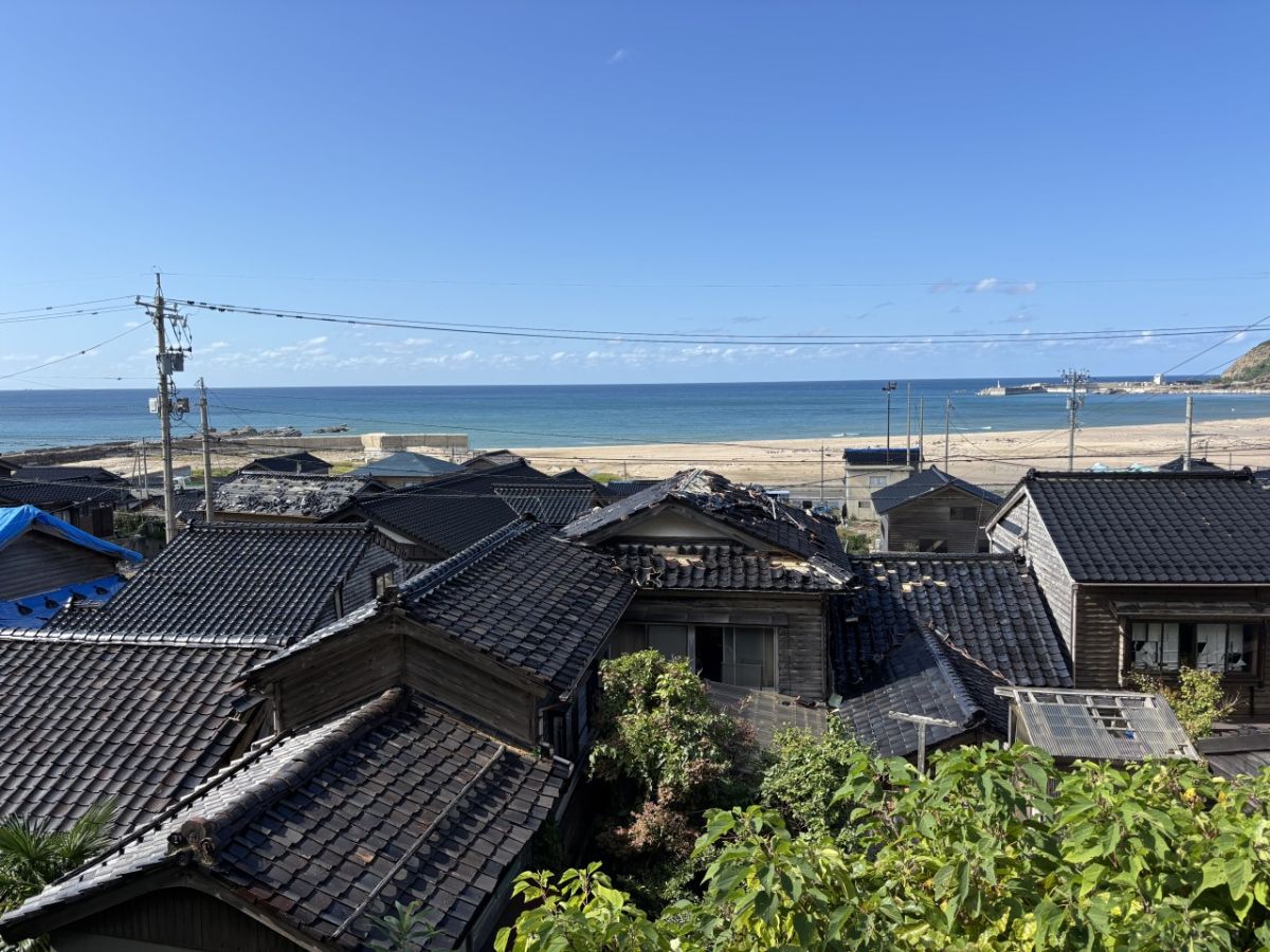 黒瓦の屋根が連なる輪島市の天領黒島地区。瓦が落ちた家屋にはビニールシートがかけられています
