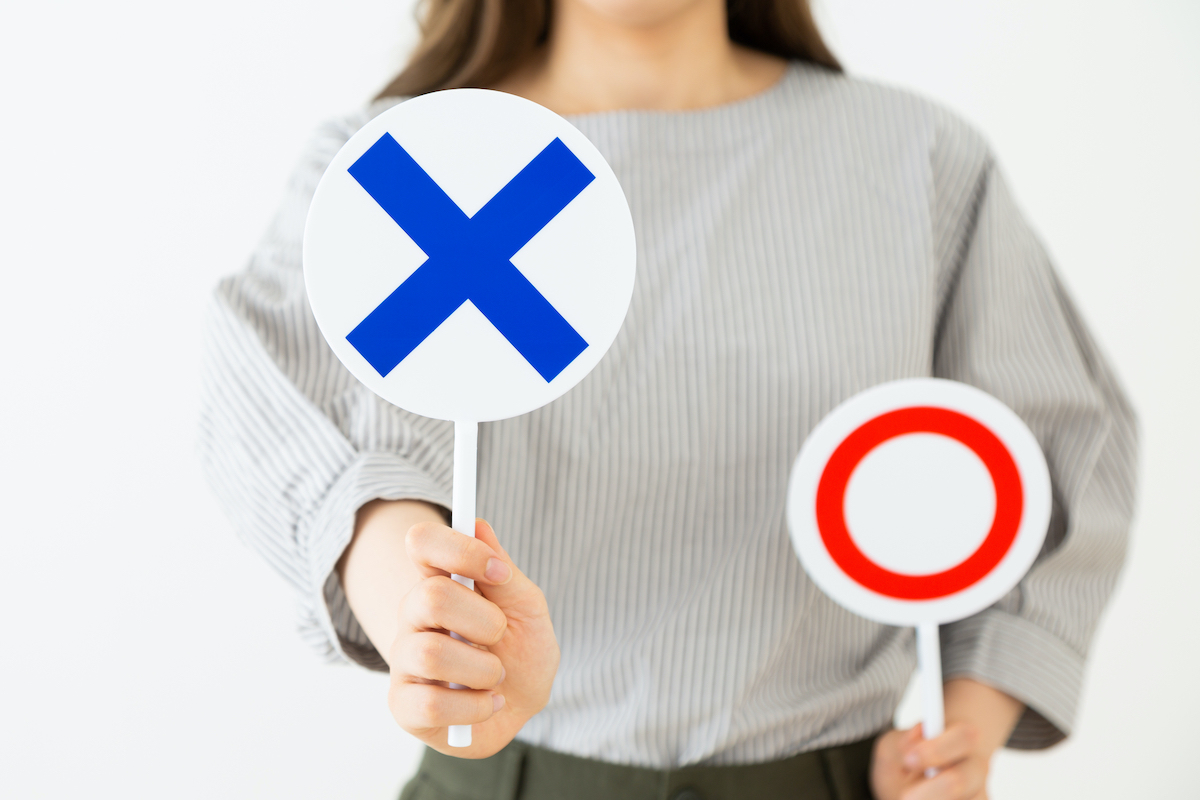 ○&times;の札を持った女性