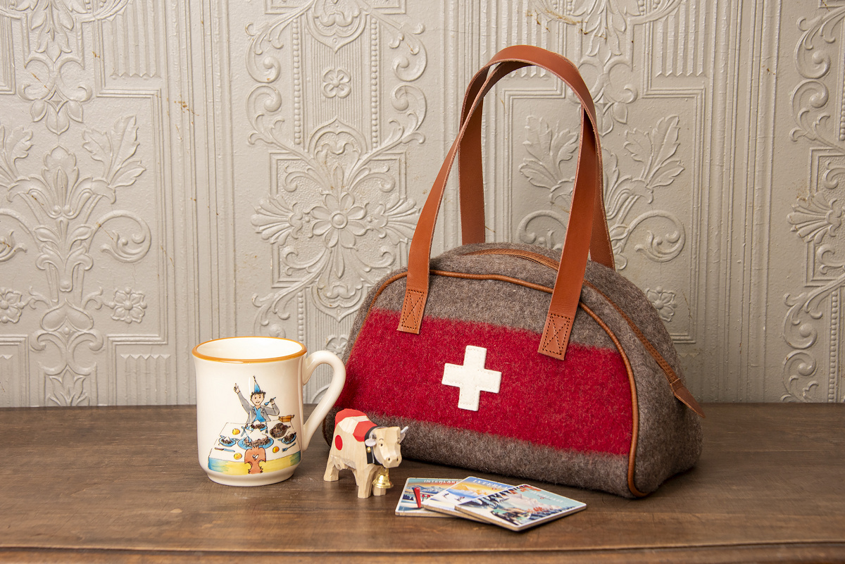 アロイス・カリジェのマグカップ（55スイスフラン）、ハンドメイドの木彫りの牛（25スイスフラン）、ステッカー（各3スイスフラン）、軍用毛布で作るボーリングバッグ（159スイスフラン）