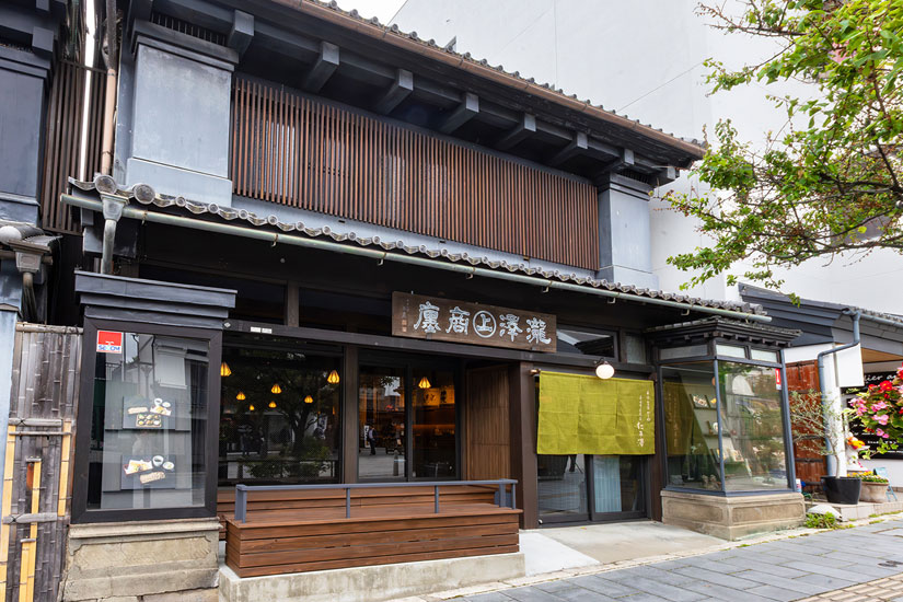 浅緑色の暖簾と信州ゆかりの書家・秋山白巌による木の看板が掲げられている