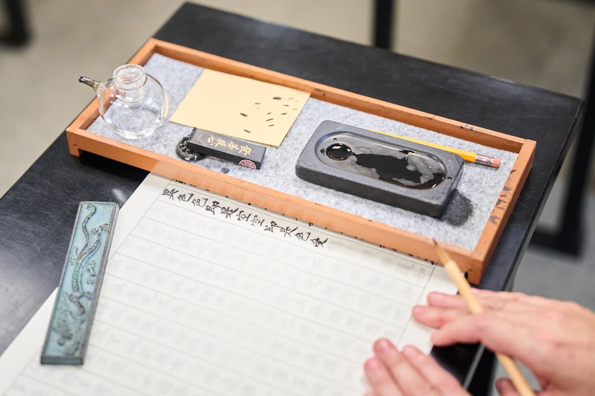 手に墨がつかないよう、筆置きの下に紙を差し込みスライドさせながら書き進められる