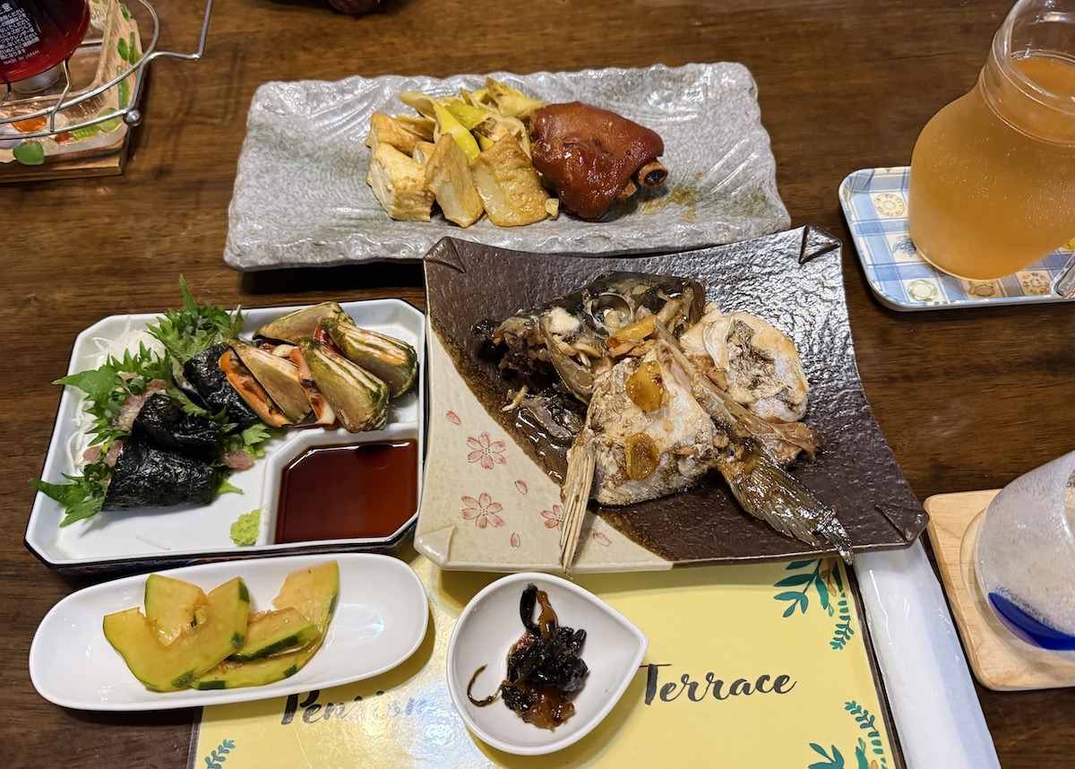 「マリンテラス」の「夕食」（3300円・要予約）。この日は島の貝「トビンニャ」や島豚の豚足、カンパチの焼き魚     など。名物「油そうめん入りのお吸い物」もセットでした ※内容は日によって異なる
