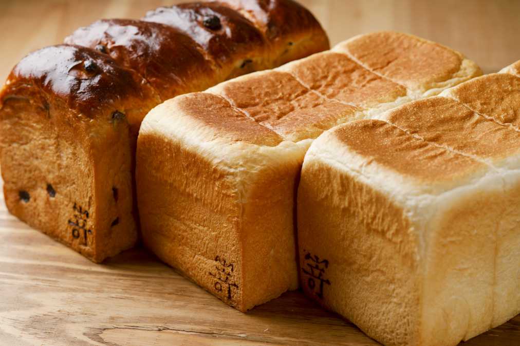 （右から）極美“ナチュラル”　900円、極生“ミルクバター”　950円、金曜限定・    “食物アレルギーの娘が安心して毎日食べられるパンを作りたい”という嵜本社長の想いからスタートしたこちらのお店。約2年をかけて完成した食パンは、「極美“ナチュラル”」と「極生“ミルクバター”」の定番2種類に加え、曜日限定の食パンがスタンバイ。   しっとりもっちり、毎日食べたいシンプルな味   （右から）極美“ナチュラル”　900円、極生“ミルクバター”　950円、金曜限定・極葡萄食パン　1300円　（すべて2斤サイズ）