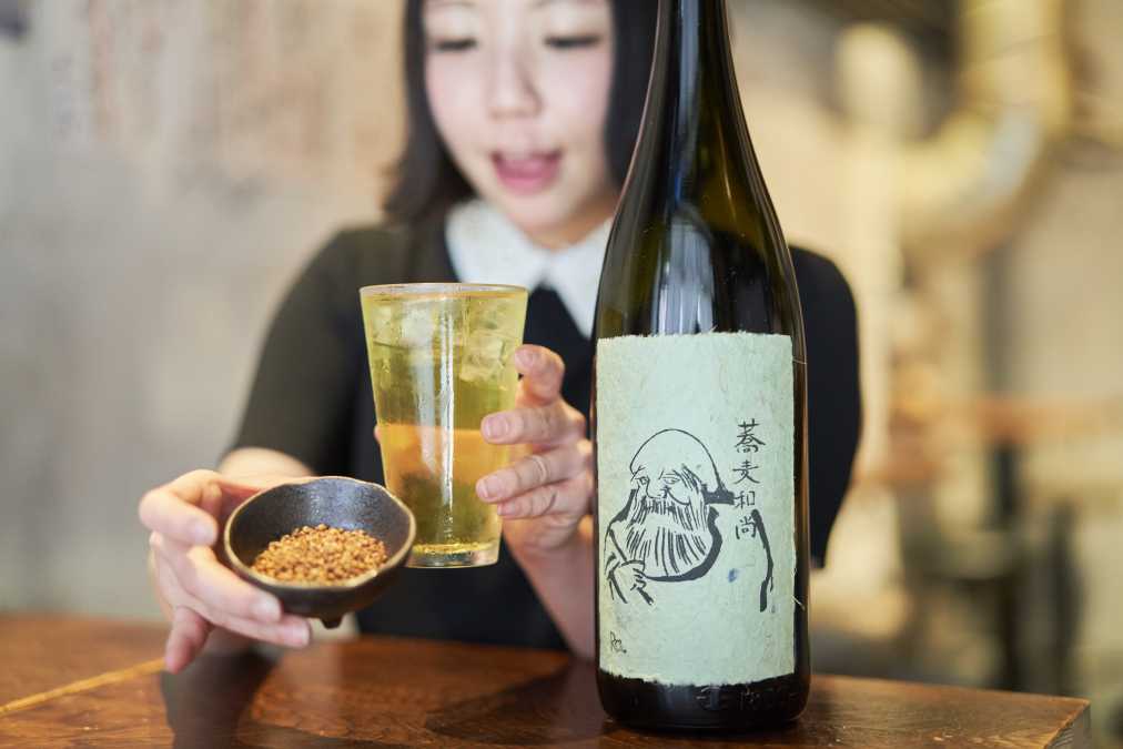 蕎麦の実と「蕎麦和尚 8年熟成」のボトルと共に